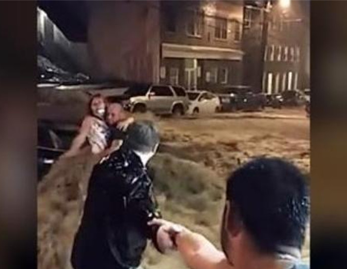 Heroic bystanders form a human chain to rescue woman from flood waters.