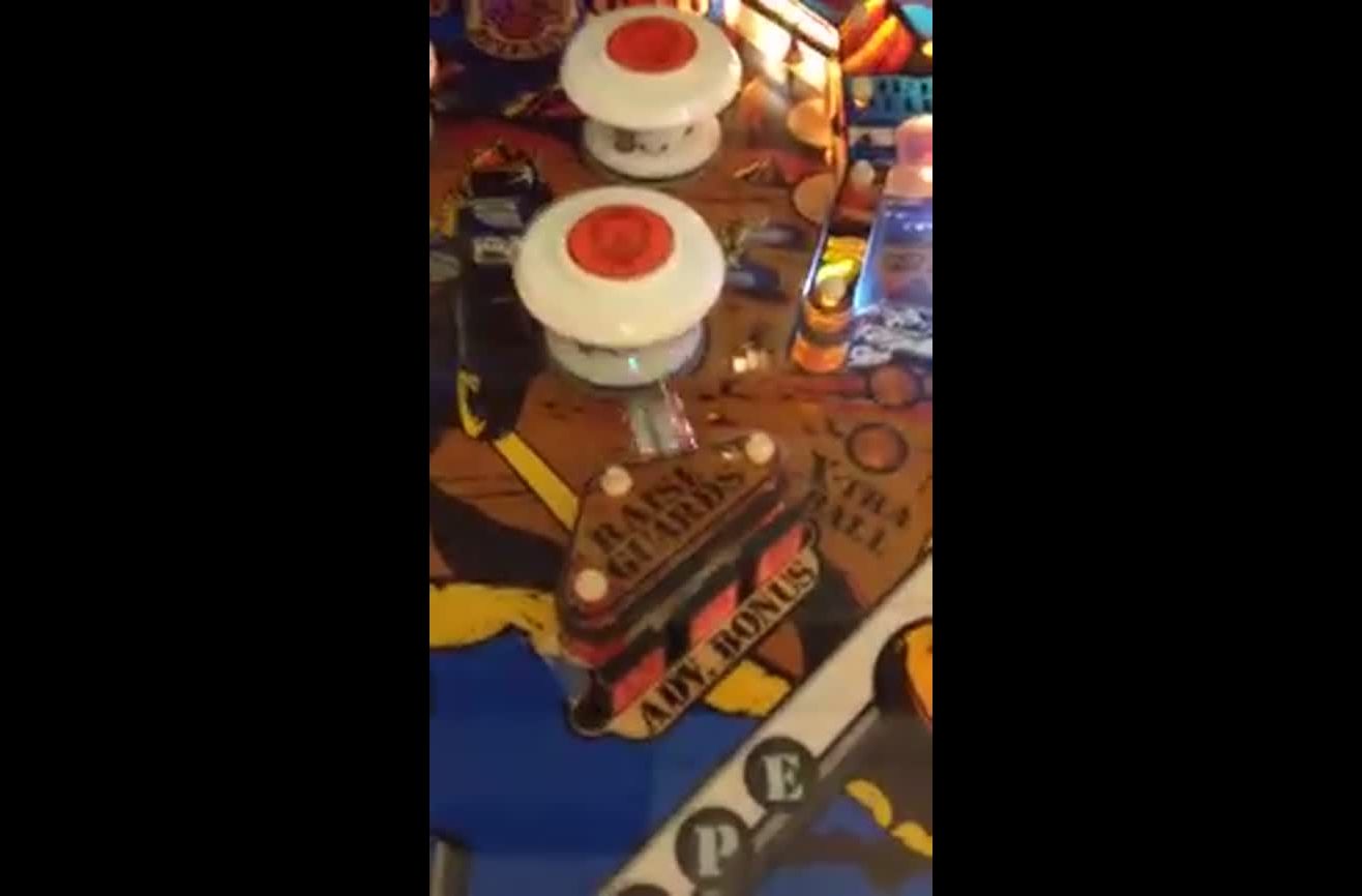 A pinball gets perfectly stuck between a bumper and kicker.