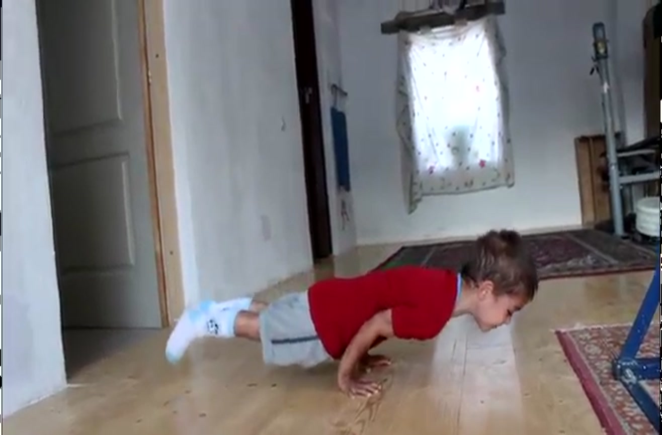 Five-year-old boy does 90 degree push-ups.