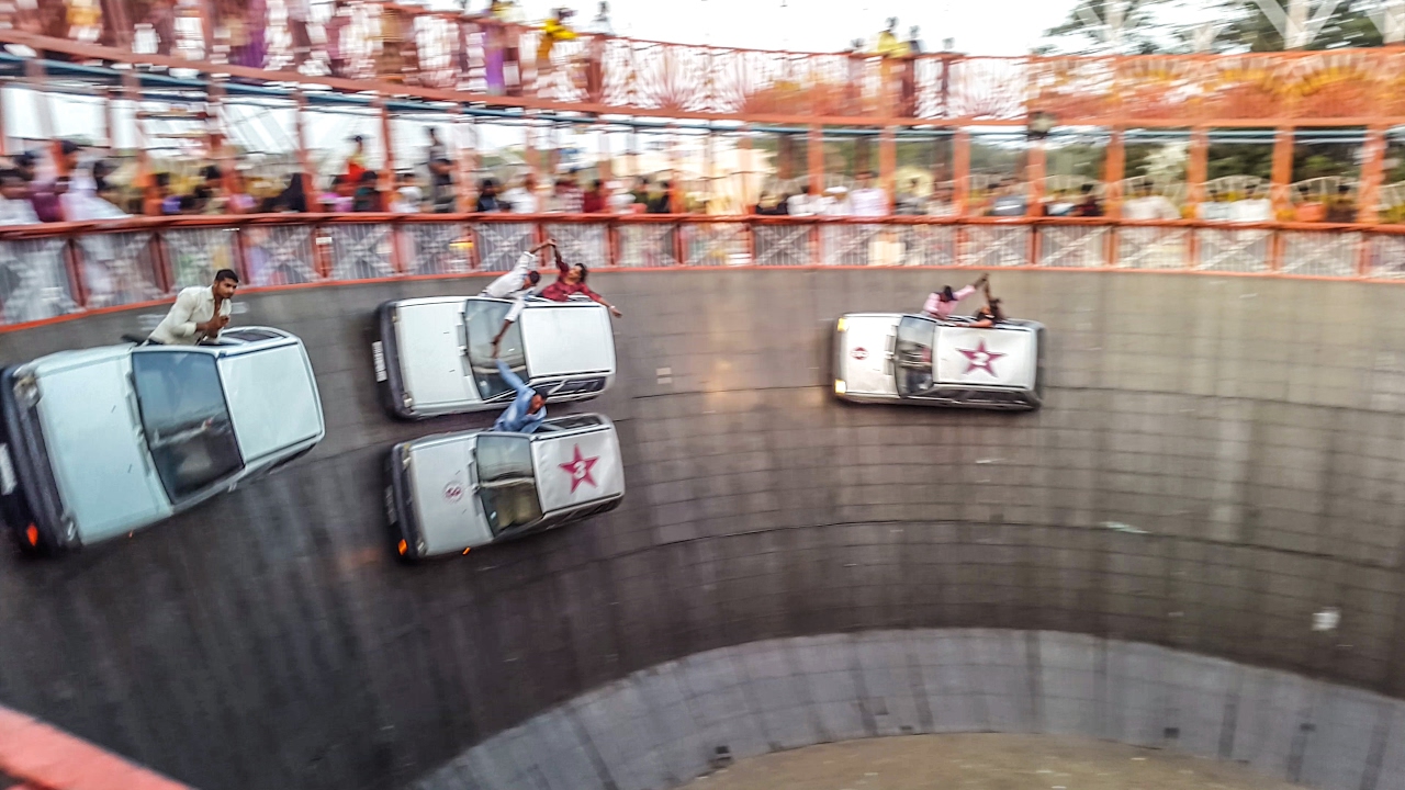 Somehow cars defy gravity while racing slowly around a cylinder